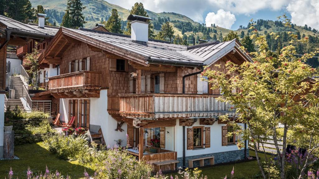 una casa de madera con montañas en el fondo en Schwaiger Alpen-Ferienwohnung auf 1800m, en Kaltenbach