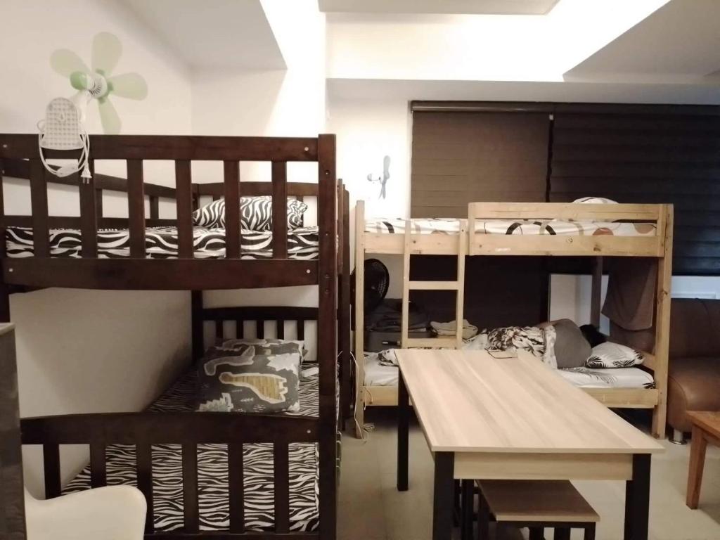 een kamer met 3 stapelbedden en een tafel bij Comfy Bunkbeds at BSA in Manilla