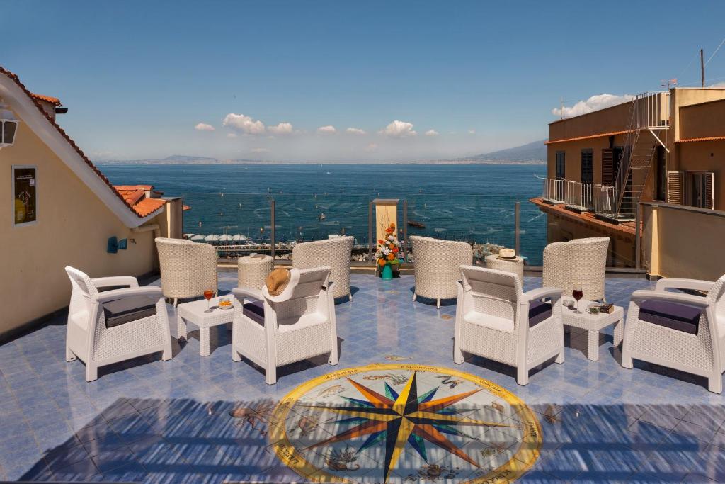 a patio with white chairs and a view of the city at Hotel Del Mare in Sorrento