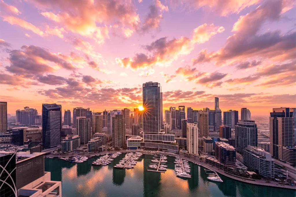 Vida Dubai Marina & Yacht Club في دبي: أفق المدينة عند غروب الشمس مع القوارب في الماء