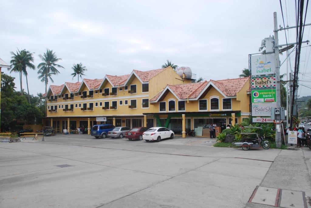 een groot gebouw met auto's geparkeerd op een parkeerplaats bij RedDoorz Plus at Balai Sofia Bed & Breakfast Batangas in Talisay