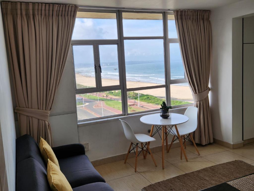a living room with a view of the beach from a window at 904 Tenbury Beach Apartment in Durban