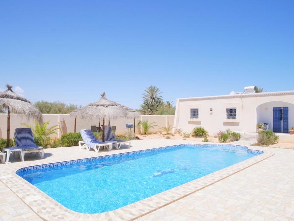 a swimming pool with two chairs and a house at Dar Elyas in Mezraya