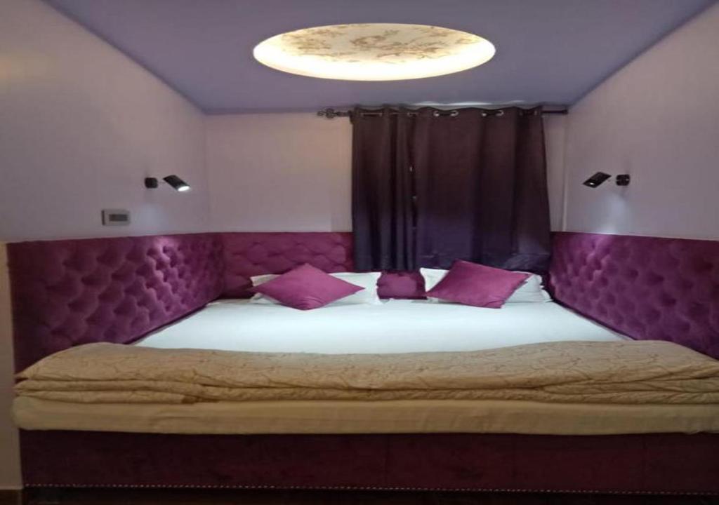 a bedroom with a large bed with a purple headboard at Maya Hotel & Restaurant in Agra