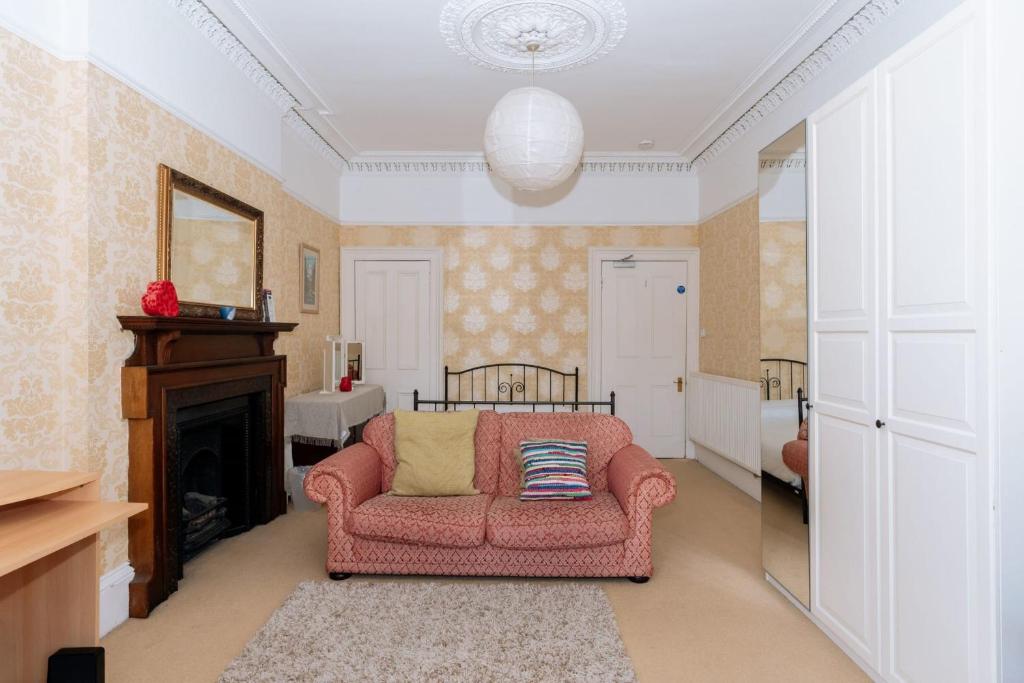 a living room with a pink couch and a fireplace at Spacious 4 Bedroom Apartment Near The MeadowsOld Town in Edinburgh