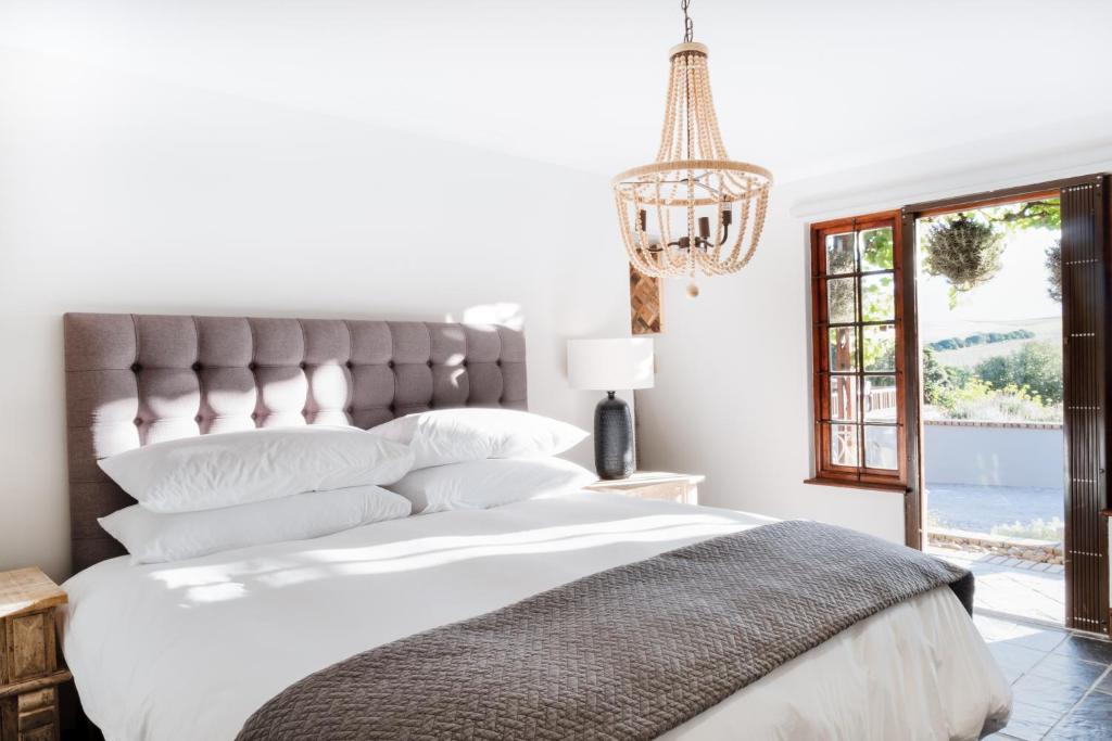 1 dormitorio con 1 cama blanca grande con lámpara de araña en Avemore Time Out - with Backup Power, en Stellenbosch