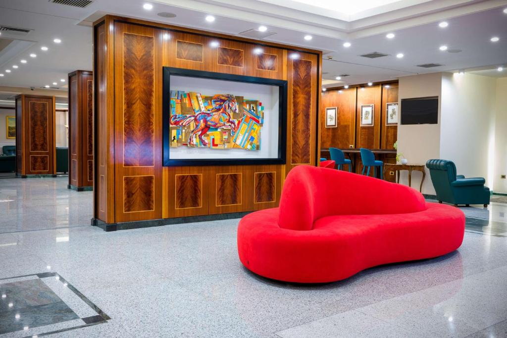 a red chair in a lobby with a painting on the wall at Best Western Hotel Ferrari in Nola