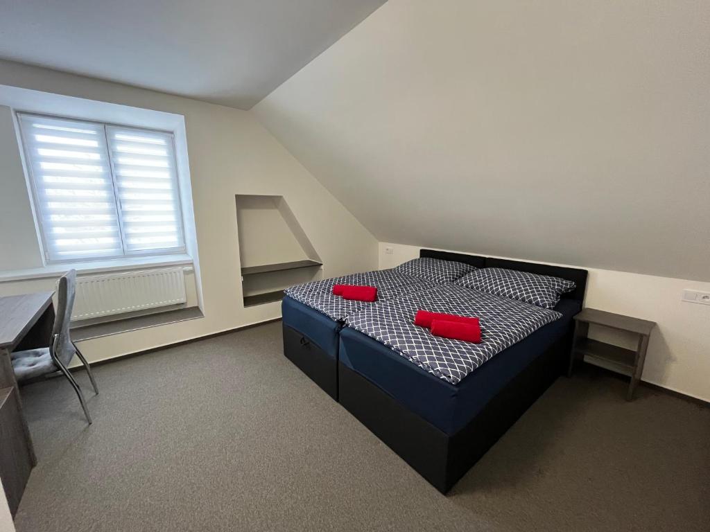 a bedroom with a bed with two red pillows on it at Penzion Sýpka in Jablŭnka