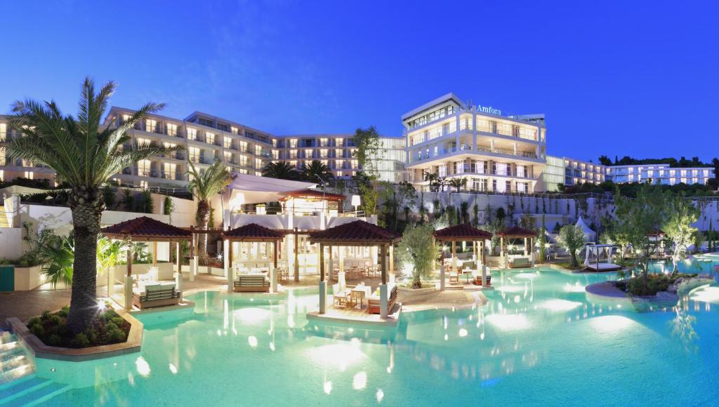 a resort with a large pool with chairs and umbrellas at Amfora Hvar Grand Beach Resort in Hvar