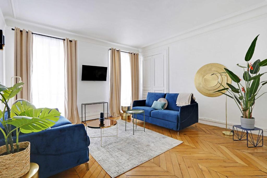 un salon avec un canapé bleu et une table dans l'établissement Classy appartment - Arc de Triomphe, à Paris