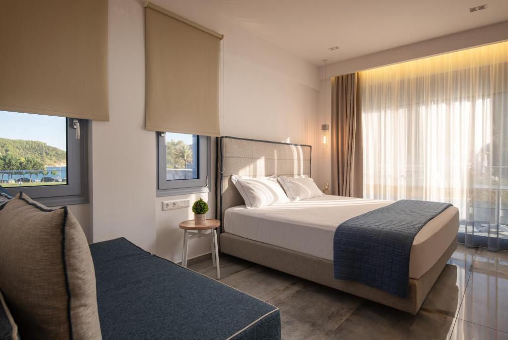 a bedroom with a bed and a couch and windows at Notia Luxury Living in Porto Koufo
