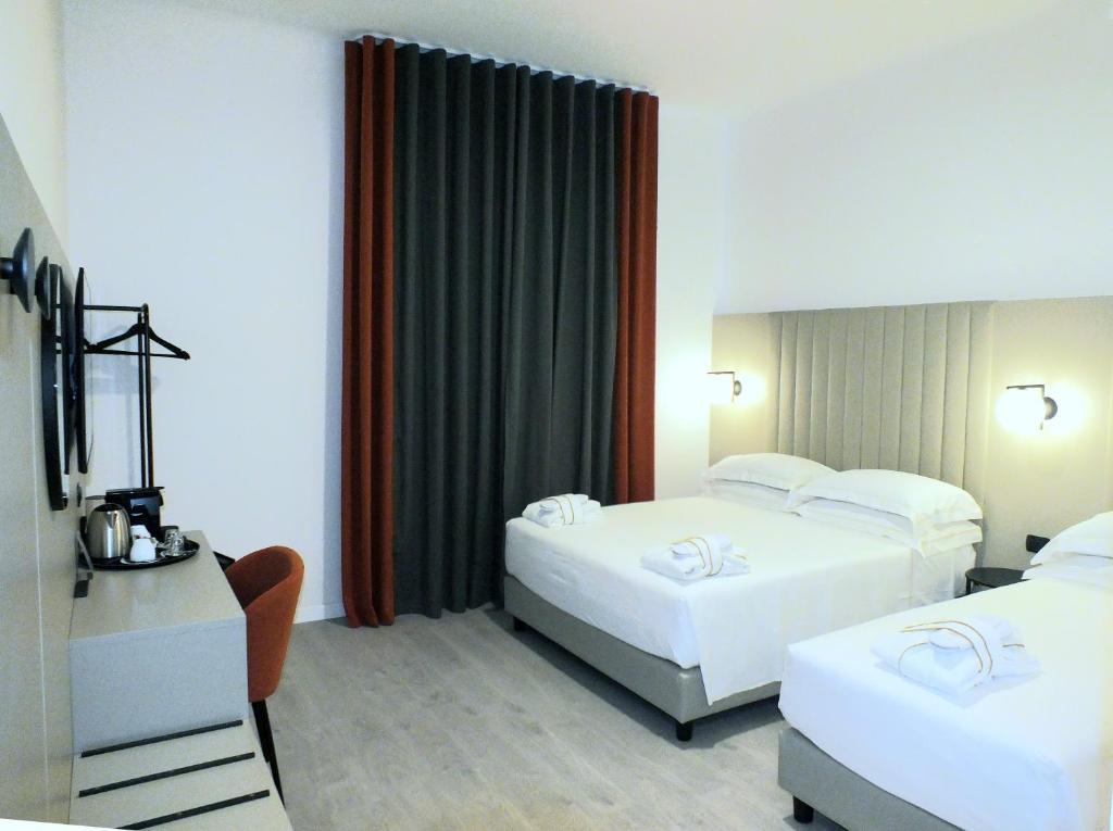 a hotel room with two beds and a desk at BB Hotels Smarthotel Derose in Florence
