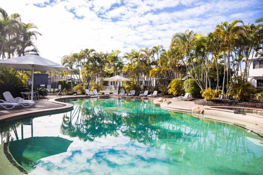uma piscina com água turquesa e palmeiras em Renovated 2 Bedroom Ground Level Villa in Noosaville em Noosaville