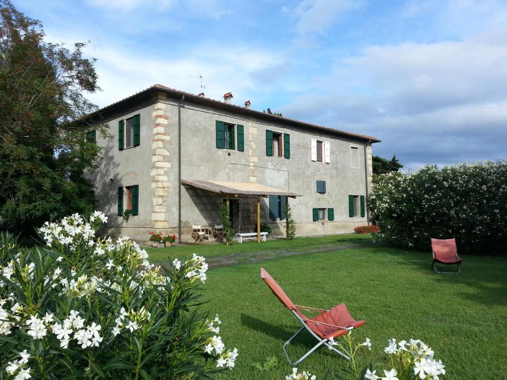 a large stone house with a yard with two chairs at Agriturismo Bella Valle in Marina di Cecina