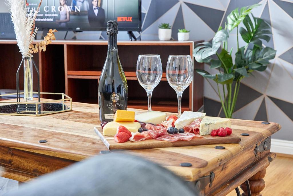 a wooden table with two wine glasses and cheese at Elite 15 Stays in Whitley Bay