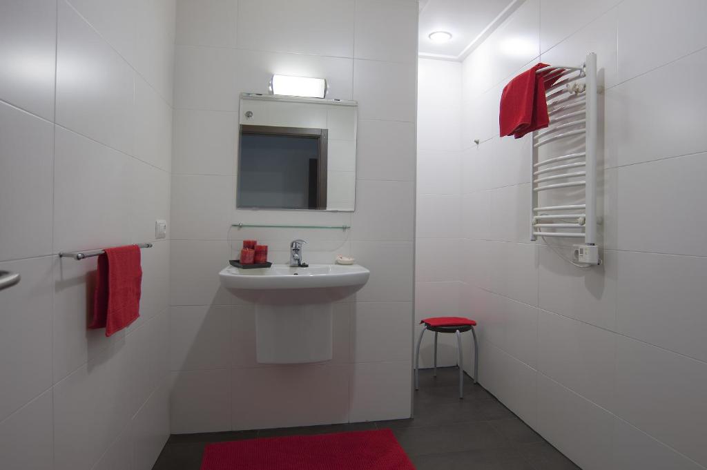 Baño blanco con lavabo y taburete rojo en Pension Guria Jatetxea en Urnieta