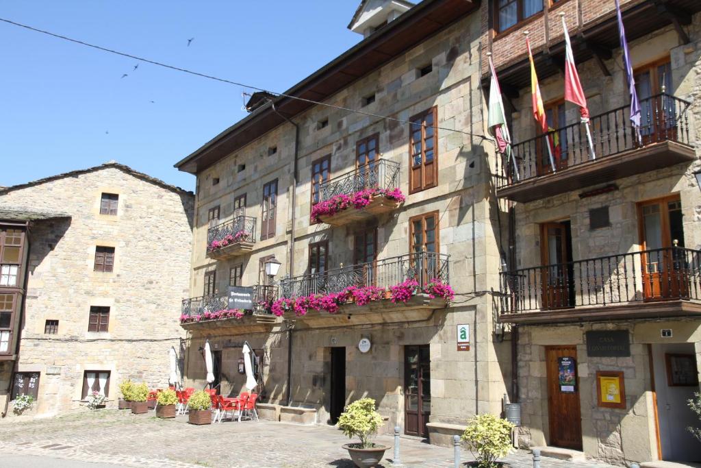 un gran edificio de piedra con macetas de flores y balcones en Posada Casa de don Guzman en Vega de Pas