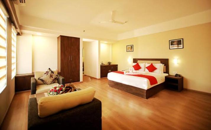 um quarto de hotel com uma cama e um sofá em Hotel kadambari em Kāladi