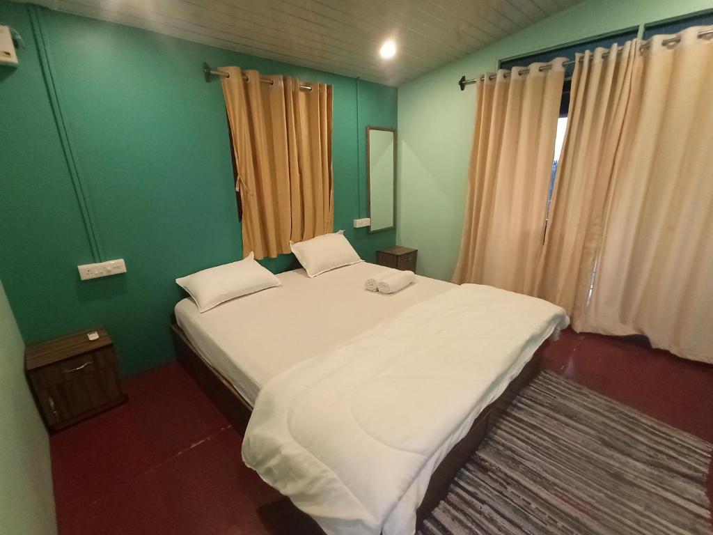 Un dormitorio con una gran cama blanca con paredes verdes. en Casa fiesta Sea front beach huts, en Patnem