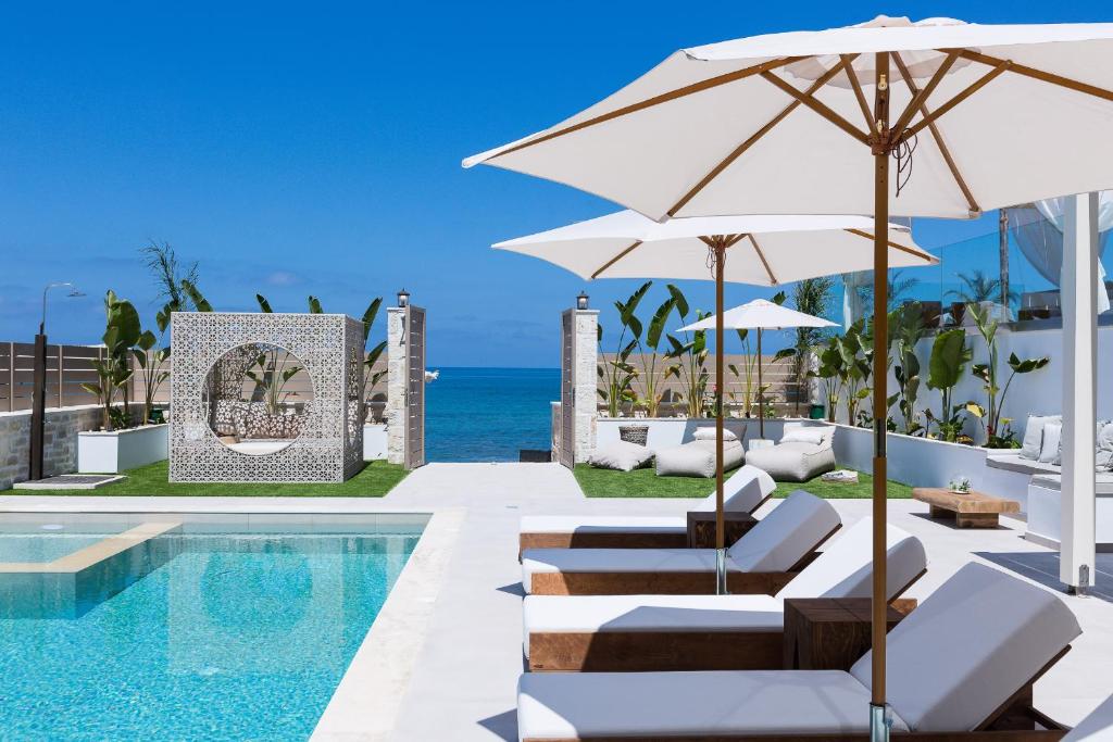 a pool with chairs and umbrellas next to the ocean at Villa Moana in Balíon
