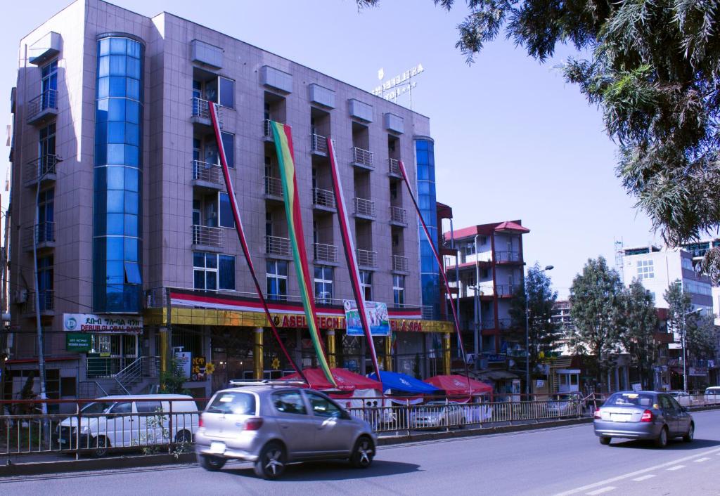 two cars driving down a street in front of a building at Aselefech Merga Hotel and Spa in Addis Ababa