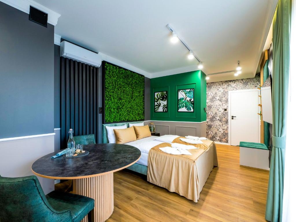 a bedroom with a bed and a table and green walls at Aparthotel Green Concrete - nowy, ekologiczny hotel w Świnoujściu in Świnoujście