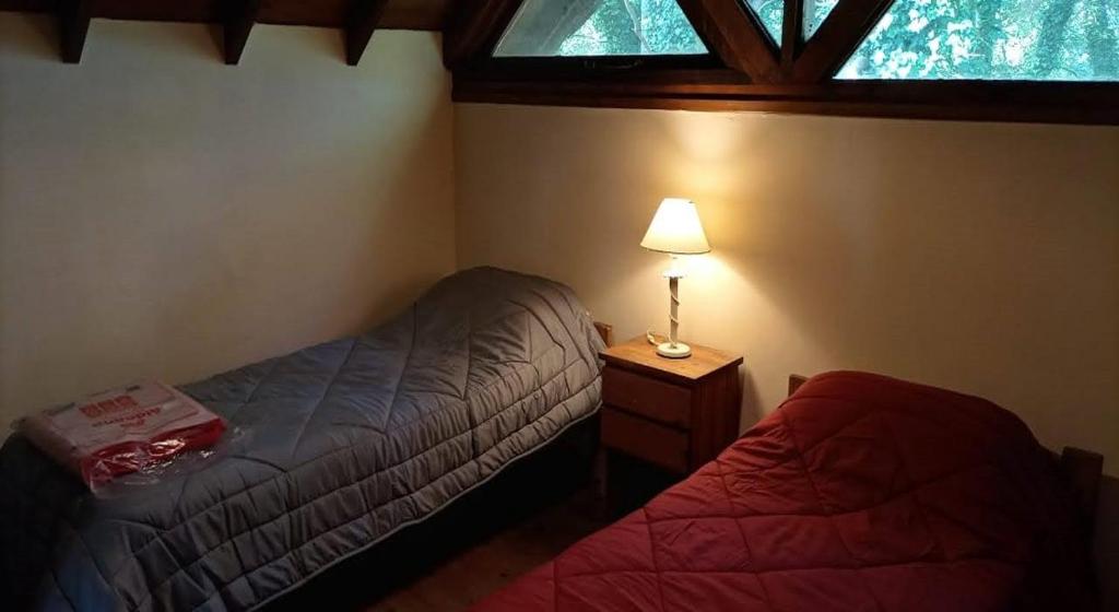 a bedroom with a bed and a lamp and a window at Cabaña de los Tres Pinos in Sierra de los Padres