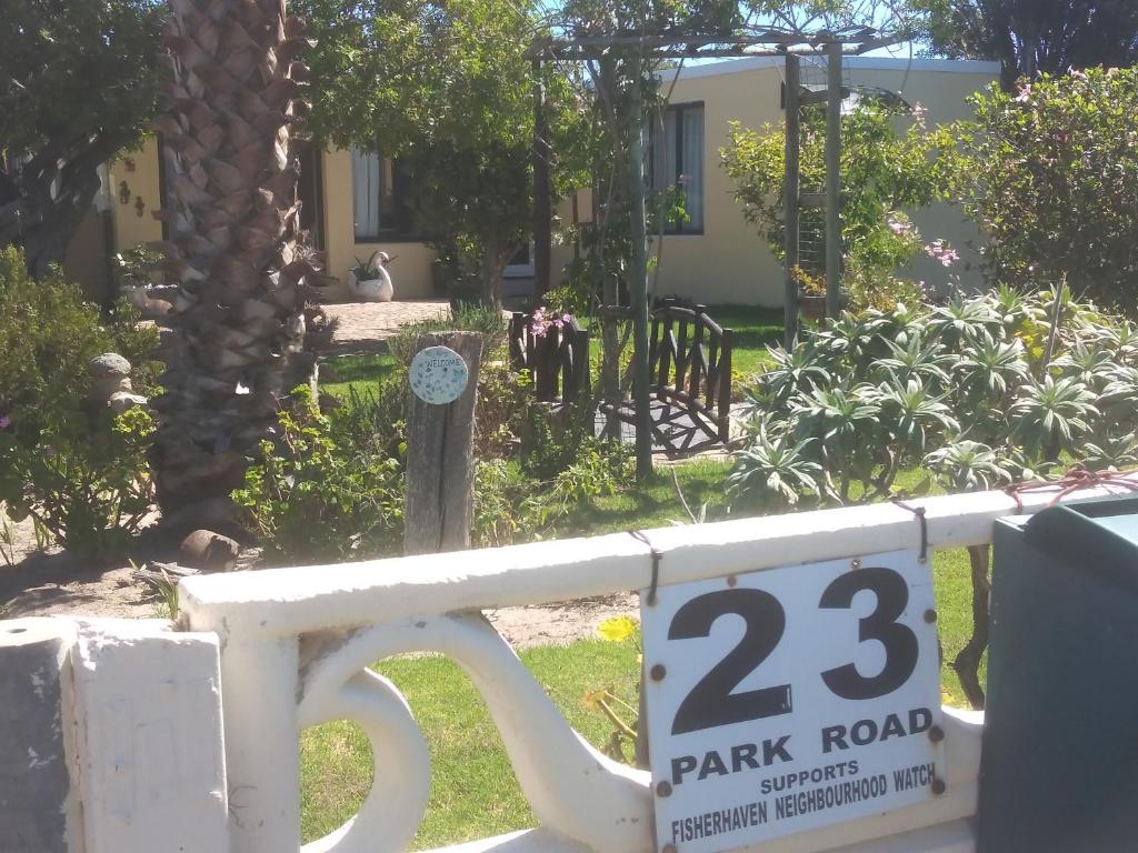 a white fence with a park road sign on it at Fisherhaven Guest House in Hermanus