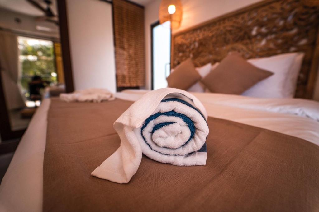 a rolled up towel sitting on top of a bed at kunaa beach Inn in Fulidhoo