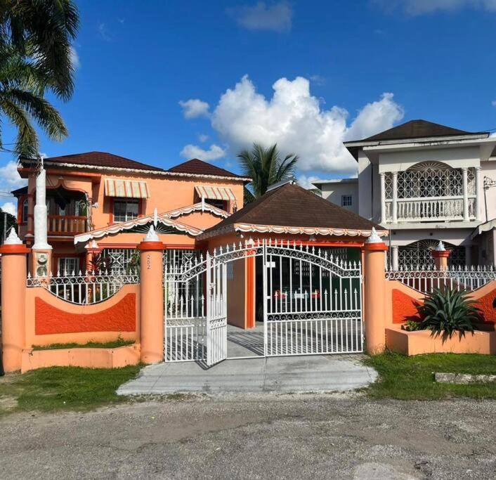 ein großes orangefarbenes Haus mit einem weißen Tor in der Unterkunft Sara’s Place - A place that feels like home in Montego Bay