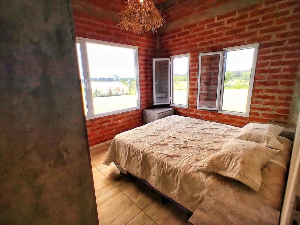 1 dormitorio con 1 cama en una pared de ladrillo en Finca L'incontro Sierra de los Padres en Mar del Plata