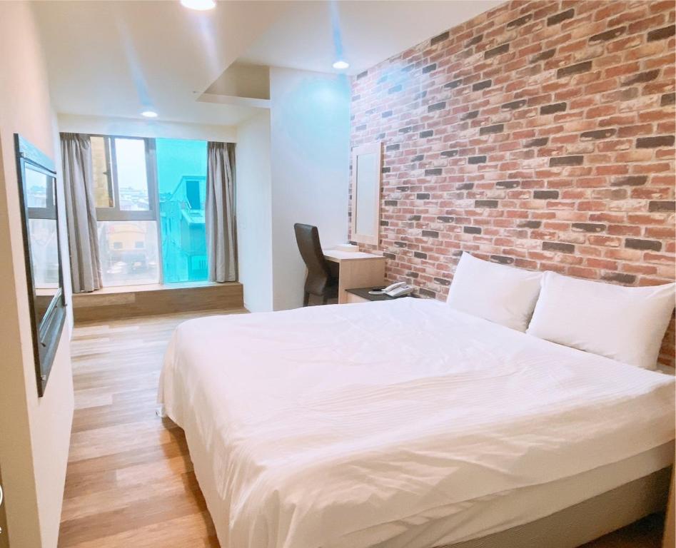 1 dormitorio con pared de ladrillo y cama blanca en E Lim Hotel, en Zhongli