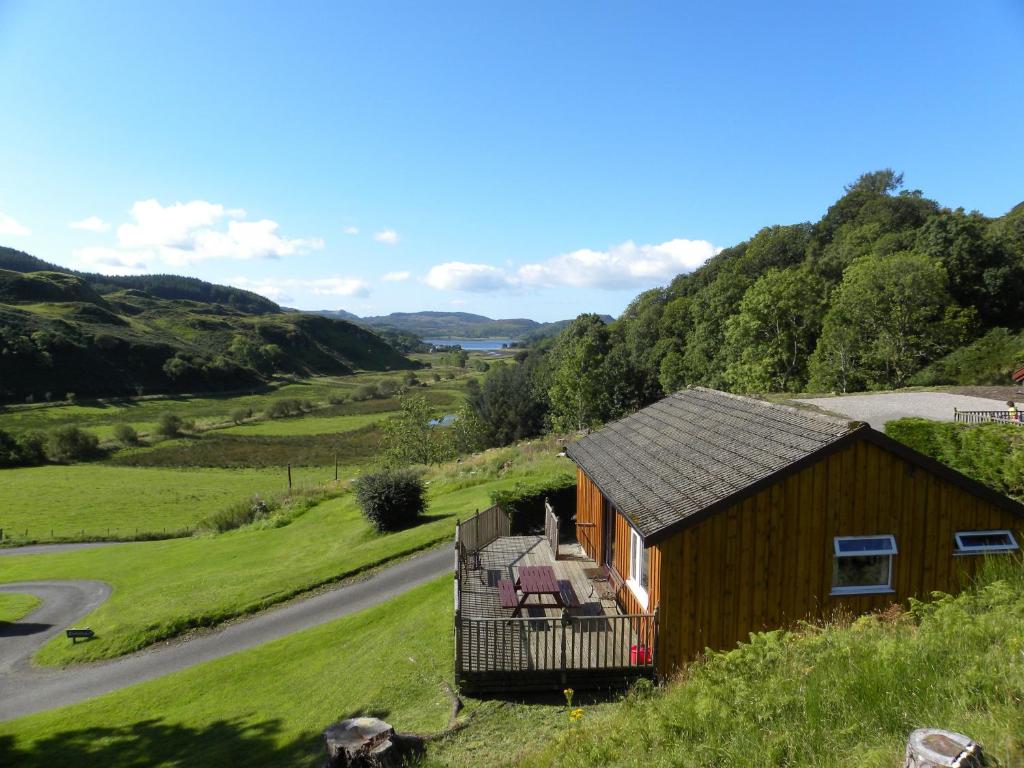 a small house on a hill next to a road at Lagnakeil Highland Lodges in Oban