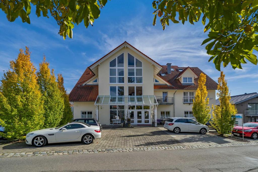 una casa con coches aparcados delante de ella en Landhaus Müller, en Immenstaad am Bodensee