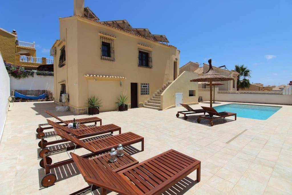 eine Terrasse mit Holzbänken und einem Pool in der Unterkunft 4 Bedroom, Luxury Villa - Heated Pool in Villamartin
