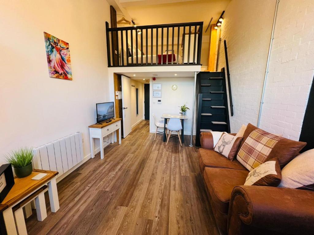 ein Wohnzimmer mit einem Sofa, einem Tisch und einer Treppe in der Unterkunft Apartment 5 Sullivan House in Hereford