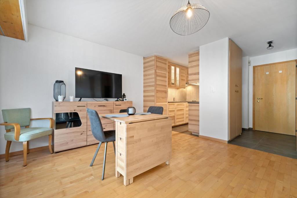 a living room with a desk with a tv and chairs at Charmant studio rénové situé dans les bains d'Ovronnaz, immeuble les Sources in Ovronnaz