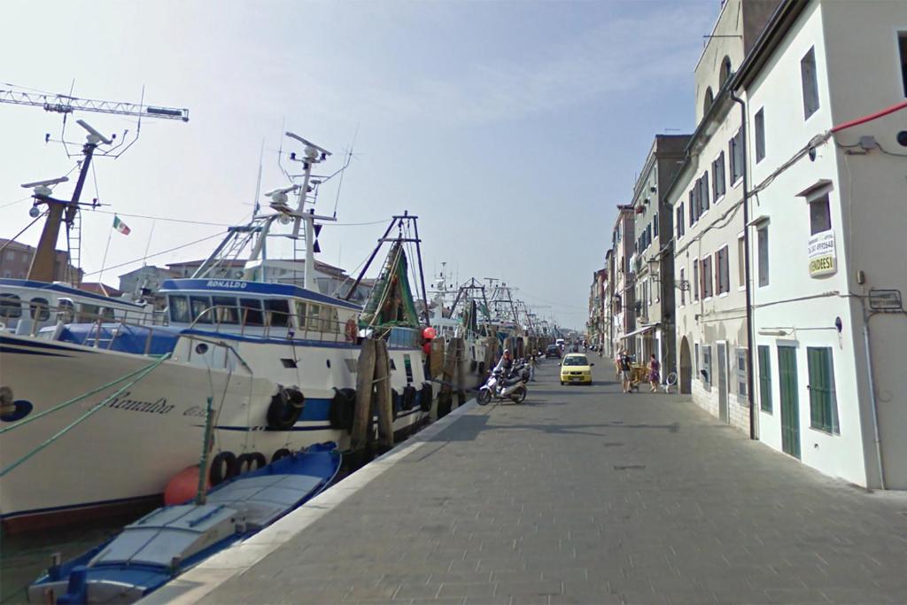 un bateau est amarré à côté d'un bâtiment dans une rue dans l'établissement Appartamento Chioggia, à Chioggia