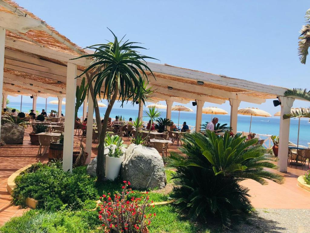 カーポ・ヴァチカーノにあるResidence Esmeraldoのビーチ沿いのレストランで、テーブル席に座る人々と一緒に食事をする