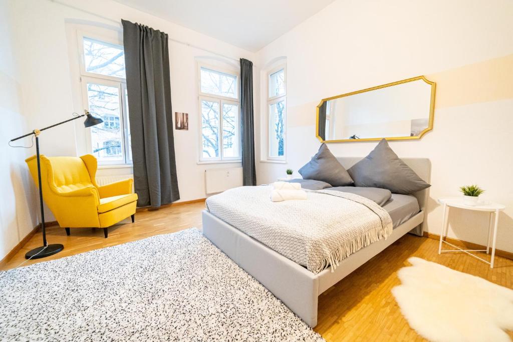 ein Schlafzimmer mit einem Bett und einem gelben Stuhl in der Unterkunft FULL HOUSE Premium Apartments Halle VS7 in Halle an der Saale