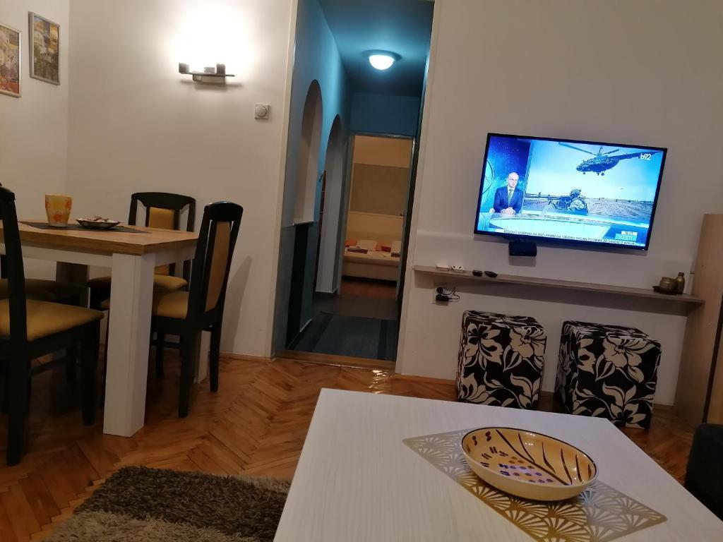 Apartman Centar في كروشيفاتس: غرفة معيشة مع طاولة وتلفزيون على جدار