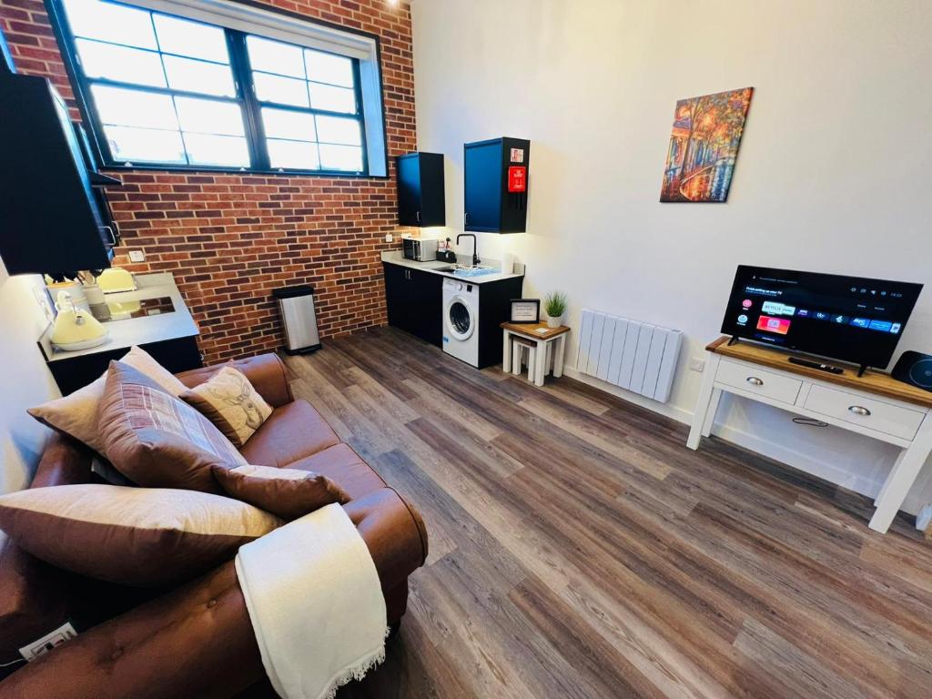 a living room with a couch and a flat screen tv at Apartment 6 Sullivan House in Hereford