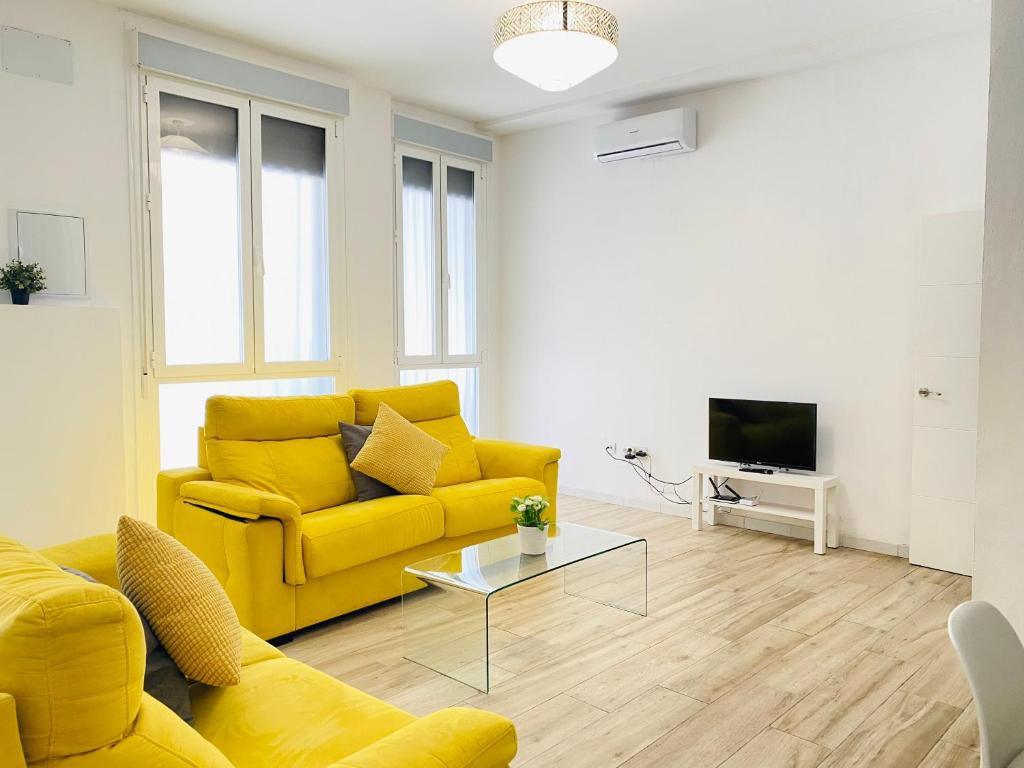 salon z żółtą kanapą i telewizorem w obiekcie Flamenca Triana - Apartamento Totalmente Equipado Wifi 2D sofas camas 2 baños w Sewilli
