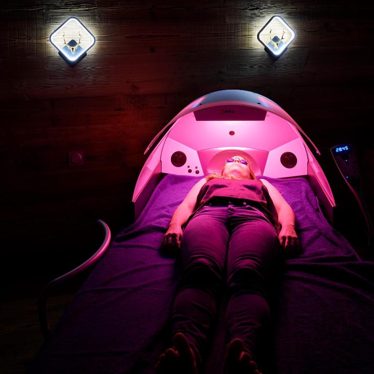 a person laying on a bed in a pink room at Logis Hôtel et Spa Le Christiania in La Salle-les-Alpes