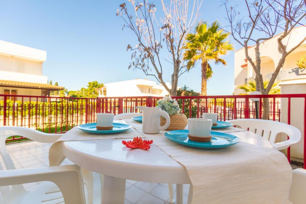 un tavolo bianco con sedie bianche e tazze di caffè di Appartamento Orchidea A1 - MyHo Casa a Torre Canne
