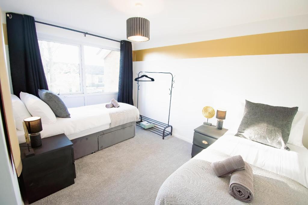 1 Schlafzimmer mit 2 Betten und einem Fenster in der Unterkunft Ideal Lodgings in Whitefield Radcliffe in Manchester