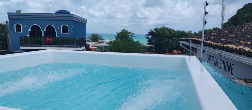 una piscina en la parte superior de una casa con el océano en el fondo en Pipa Arara House - Por Pipa Casas de Praia, en Pipa