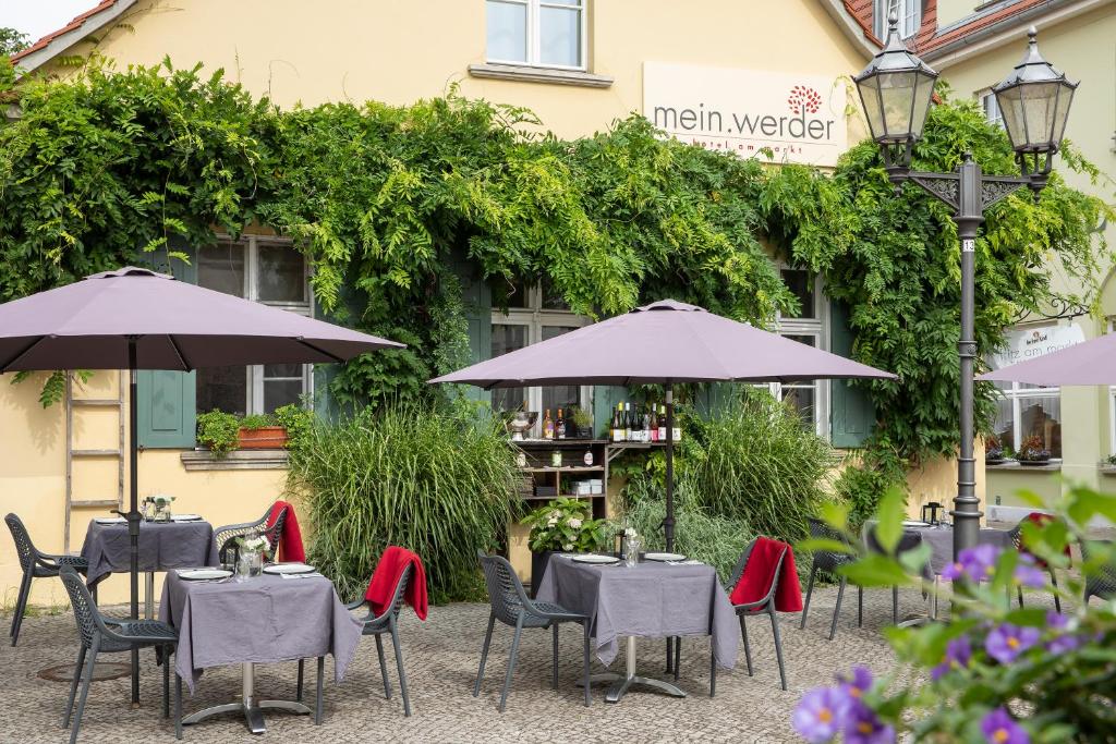 um restaurante com mesas e guarda-sóis em frente a um edifício em mein werder - hotel am markt em Werder