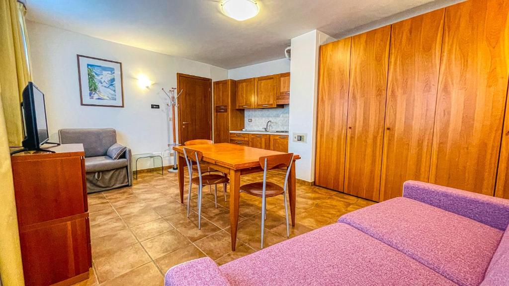 salon ze stołem i fioletową kanapą w obiekcie Appartamento Smith Erbaluce - Affitti Brevi Italia w mieście Bardonecchia