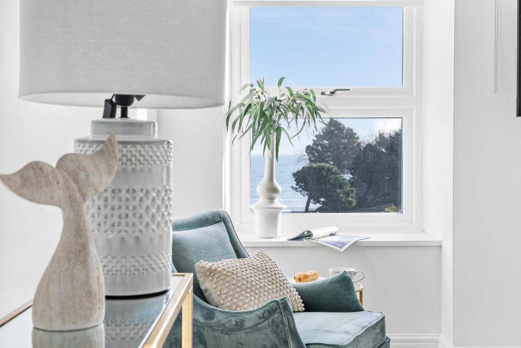 uma sala de estar com uma cadeira, um candeeiro e uma janela em Seaview Suite at The Corbyn Apartments em Torquay